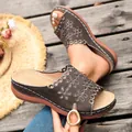 Detailed view of women's wedge sandals with hollow floral patterns and thick soles - Brown