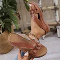 Gros plan détaillé de sandales compensées marron vintage avec motifs floraux ajourés - Brun Foncé