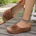 Detail of brown women's wedge slippers with 3D flower accent and white stitching - Brown