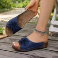 Close-up of blue wedge slippers featuring a decorative 3D flower and white stitching - Blue