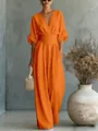 Detail of an elegant orange V-neck jumpsuit with a cinched waist and wide legs for summer. - Orange