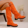 Detailweergave van oranje kniehoge plooilaarzen met zilveren gespen en lage hak. - 35 / Hoge Ridderlaarzen / Oranjerood