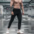 Close-up of black quick-dry athletic joggers on a muscular male model outdoors - S / Bottoms / Black