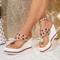 Detailed view of white wedge sandals featuring red rhinestones and pearl flower ornaments - 38 / Red