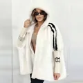 Close-up detail of women's white faux fur hooded jacket with black stripes and logo - 2XL / Tops / White