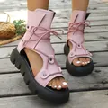 Rosa Schnür-Römersandalen mit dicker Plattform und Peep-Toe-Design auf Holzterrasse - Rosa