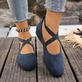 Close-up of navy blue suede flats featuring elastic cross straps for a secure fit. - Blue