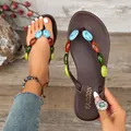 Primo piano di infradito piatte marroni con decorazioni in pietre multicolori. - 36 / Marrone scuro