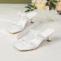 Eleganti sandali bianchi con tacco a spillo basso, punta quadrata e fiocchi decorativi. - 38 / Bianco
