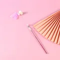 Detail van een feeën-kattenstokje met roze veren, bellen en kralen op roze achtergrond. - Roze