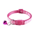 Close-up van roze kattenhalsband met pootafdrukken, kattenvormige gesp en paarse bel - Kattenkop Gesp Stijl / Rozerood