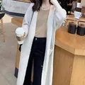 Detailed view of women's long thick knit cardigan sweater worn in a cozy cafe setting - One Size / Tops / White