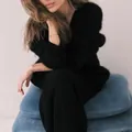 Close-up detail of a soft black mink velvet V-neck knitted sweater on a seated model - Black