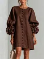 Detail view of brown linen dress featuring 3D floral appliqués on lantern sleeves. - Brown