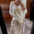 Detail view of women's white long-sleeve top with golden eye and metallic pants set. - Top And Bottom / Gold / 3XL