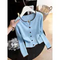Detailed close-up of a light blue knitted cardigan featuring brown trim and buttons. - One Size / Tops / Blue