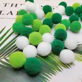 Interactive soft green and white plush cat toy balls scattered on a palm leaf background - Green Series
