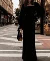 Elegant long-sleeved U-neck black evening gown with mermaid silhouette in city setting. - Black