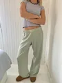 Lässige, hellgrüne Hose mit hoher Taille und Streifen-Shirt in gemütlicher Wohnumgebung - Hellgrün