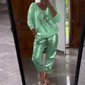 Woman wearing a stylish shiny light green 2-piece lounge set with sequined eye graphic - Top And Bottom / Green / 3XL