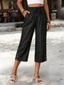 Detail view of dark denim cropped wide-leg pants with elastic drawstring waist and buttons. - S / Bottoms / Black