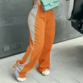 Detail einer zweifarbigen, weit geschnittenen Jogginghose für Damen in Orange. - Orange