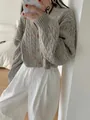 Dettaglio di un cardigan grigio spesso a trecce con bottoni in una camera da letto - Taglia unica / Top / Grigio