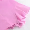 Détail rapproché du bord à volants en coton rose sur un ensemble de vacances chic - S / Haut Et Bas / Rose