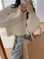 Primo piano di un cardigan a trecce color panna indossato con jeans e una borsa - Taglia unica / Top / Bianco