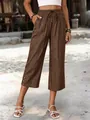 Model trägt braune, weite verkürzte Tencel-Hose mit Tasche und Knöpfen im Freien - Braun
