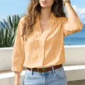 Camicia casual a righe arancioni con scollo a V da donna in un ambiente costiero - Arancione