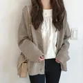Primer plano de una acogedora chaqueta de punto beige con botones grandes en una modelo asiática. - Talla única / Tops / Albaricoque