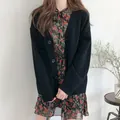 Primer plano de un cárdigan de punto negro minimalista sobre un vestido de flores. - Talla única / Tops / Negro