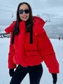 Stijlvol rood kort gewatteerd jack met capuchon voor dames in een besneeuwd skigebied - Rood