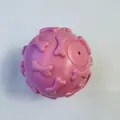 Detailed view of pink TPR squeaky dog ball with raised bone patterns for dental care. - Macaron Pink Bone Ball
