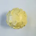 Detailed macro view of a durable yellow TPR squeaky dog toy ball with 3D bone patterns - Macaron Yellow Bone Ball