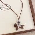 Macro view of a brown enamel dachshund dog necklace pendant with a silver bow detail - Coffee