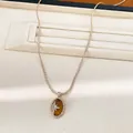 Nahaufnahme einer Halskette mit Tigerauge und einem funkelnden Stern aus Zirkonia. - Halskette / Hellkaffeegold