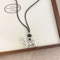 Detailed macro view of dalmatian puppy pendant necklace with bow on a wooden display tray - Black and White