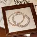 Nahaufnahme eleganter runder Perlenarmbänder mit Strass-Abstandhaltern in einer braunen Samtschale - Weiß Zweiteiliges Set (HB7123)