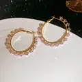 Exquisite detail view of golden hoop earrings featuring sparkling pink square-cut zircon stones - Pink