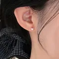 Close-up of minimalist silver heart stud earring worn on ear with black hair background - Heart Shape (HE35956) / 925 Silver Earring Post / Silver