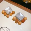 Détail macro de boucles d'oreilles ethniques avec résine blanche et perles en bois naturel - Style Ethnique Vintage (HE35848-1) / Aiguille en argent / Argent/Blanc/Brun