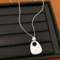 Detailaufnahme einer silbernen Halskette mit organischem Anhänger auf schwarzem Samt. - Halskette / Matt Silber