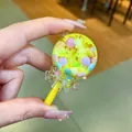 Detailopname van een lolly-vormige olieschudbedel met gele glitters en gekleurde kralen. - Zonder Sleutelhanger (1 Stuk) / Gele Lichtgevende Lolly