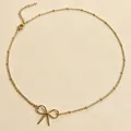 Gedetailleerd overzicht van een gouden strikhanger aan een fijne kralenketting choker - Goud