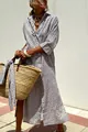 Woman wearing a patterned maxi shirt dress styled with a woven straw bag outdoors - Grey Rhombus
