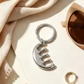 Macro detail of a minimalist silver stainless steel comb-shaped keychain on beige board - Comb Shaped / Steel
