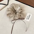 Close-up of a vintage beige polka dot scrunchie with a brown ribbon bow detail. - Scrunchie (Beige) / Beige