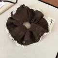 Close-up of brown polka dot scrunchie with white ruffled edges and gold charm. - Scrunchie (Dark Coffee) / Dark Coffee